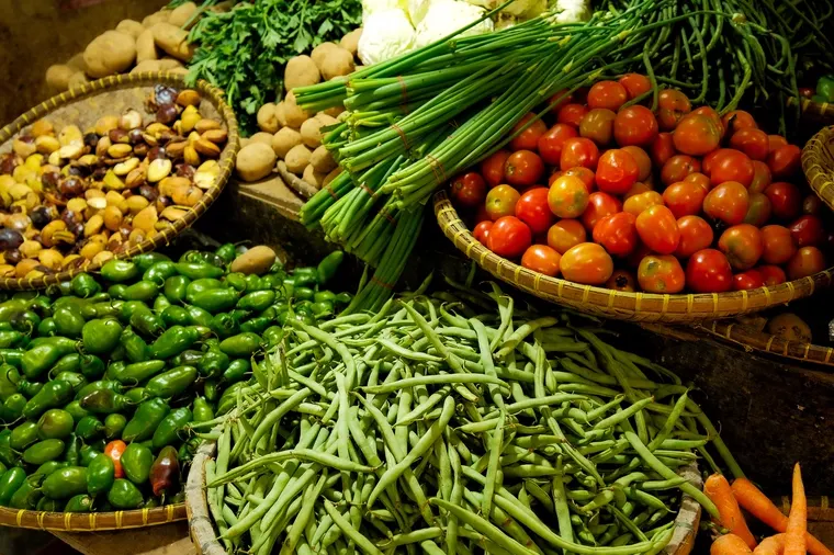 Baskets of green beans, tomatoes and spring onions on a market table