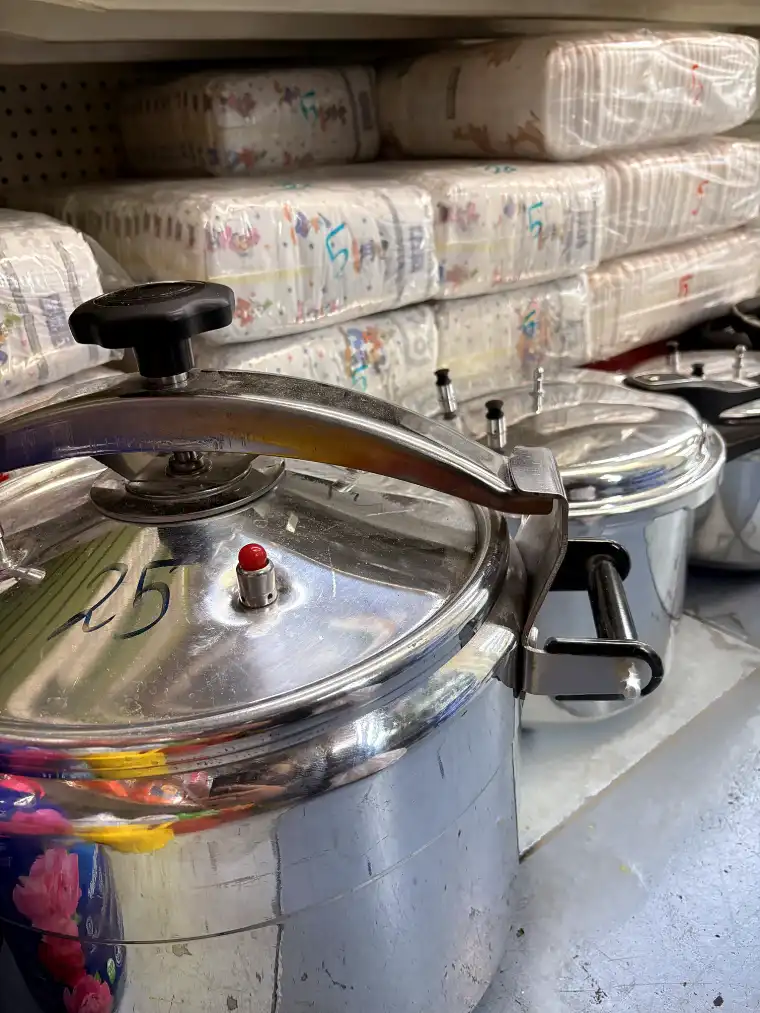 Stainless steel pressure cookers stacked on the shop shelf