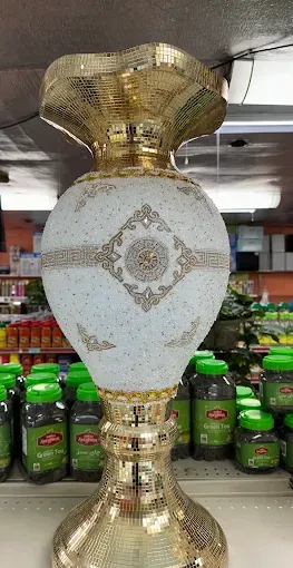 A gold and white decorative vase on a shop shelf