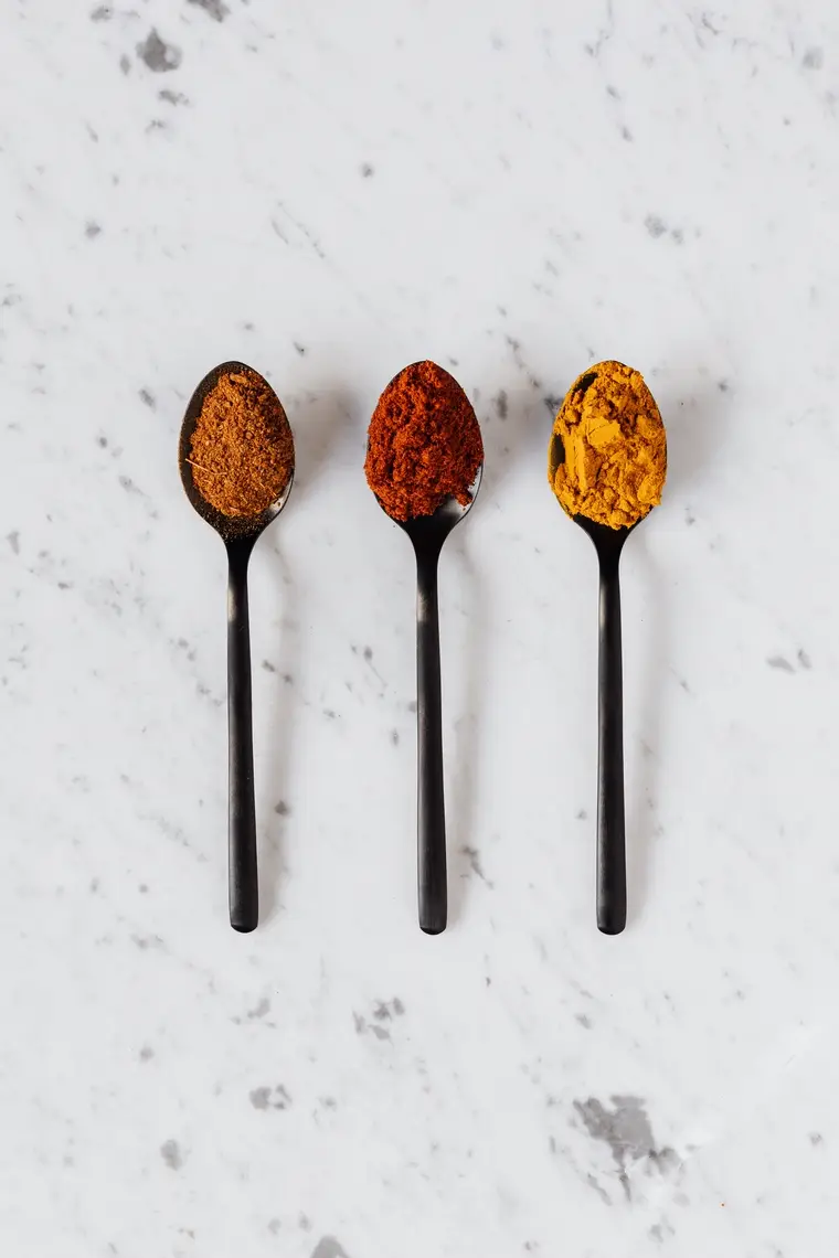 Three spoons of different ground spices on marble